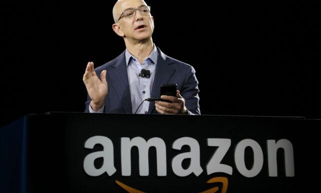 FILE - In this Wednesday, June 18, 2014, file photo, Amazon CEO Jeff Bezos demonstrates the new Amazon Fire Phone, in Seattle. Amazon is buying Whole Foods in a deal valued at about $13.7 billion. The two companies have not yet detailed how their proposed union might change the experience for customers. But the deal has the potential to boost the outsized ambitions of Amazon CEO Jeff Bezos and Whole Foods chief John Mackey, each of whom has already radically altered the way Americans shop. (AP Photo/Ted S. Warren, File)
